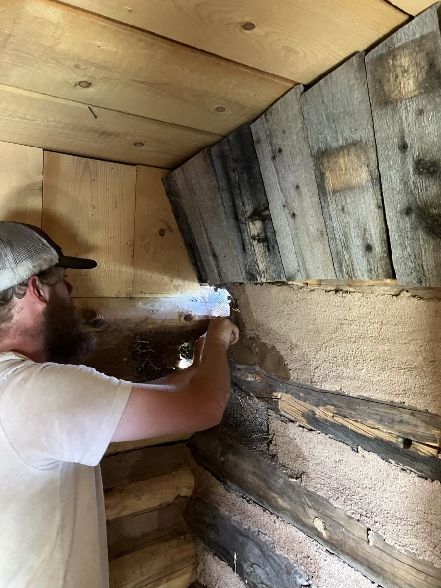 Crew member repairing logs inside a historic cabin